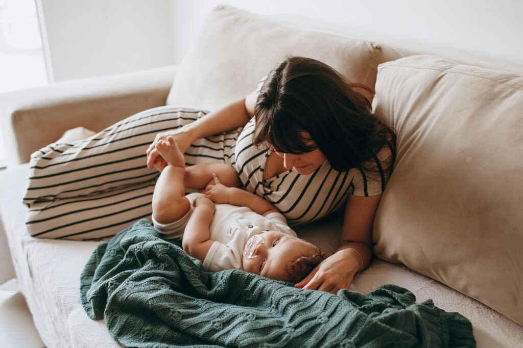 A warm moment of a mother and baby lounging on a comfortable sofa indoors.