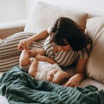 A warm moment of a mother and baby lounging on a comfortable sofa indoors.